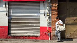 Mujer camina frente a una tienda de la colonia 10 de mayo, en Puebla.