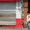 Mujer camina frente a una tienda de la colonia 10 de mayo, en Puebla.