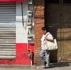 Mujer camina frente a una tienda de la colonia 10 de mayo, en Puebla.