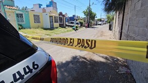 Cinta policiaca acordonando una calle donde hallaron un cuerpo embolsado con casas y patrullas de la Policía de Tlajomulco alrededor