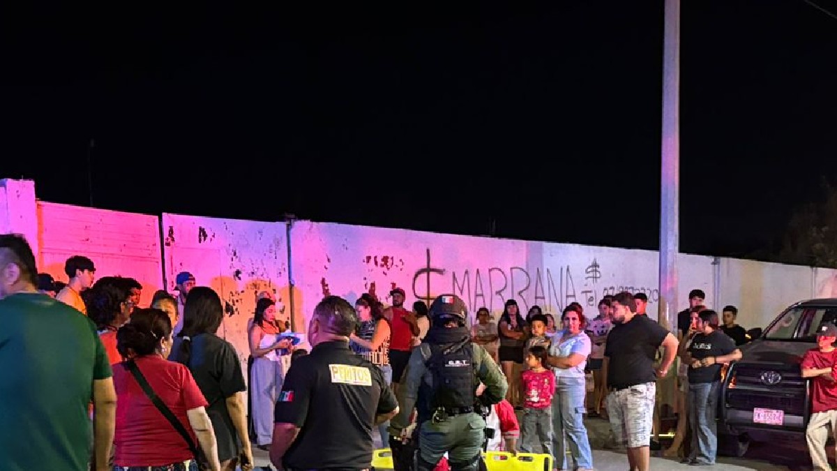 Varias personas en la calle de noche junto a una camilla de accidentado