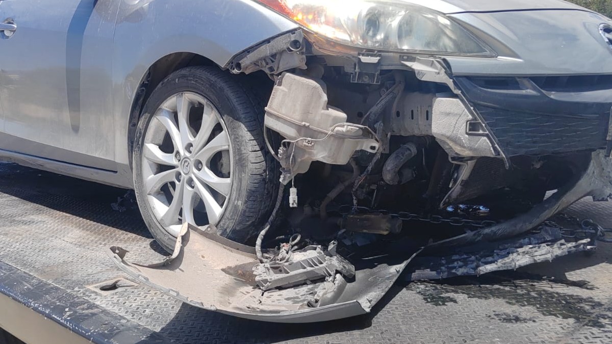 Auto en color gris chocado arriba de una grúa