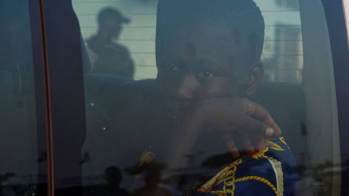 Niño de Nigeria con el rostro apoyado en su mano mientras mira a través de una ventana dentro de una patrulla de la policía