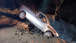 Camioneta color gris a punto de caer por el borde de una barranca con la tierra deslavada debajo en Huentitán
