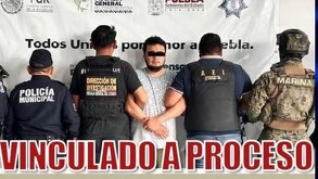 Hombre presentado para una fotografía, asegurado por policías y militares.