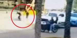 Imagen de hombres en motocicleta disparando hacia dos personas en la banqueta.