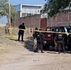 Oficiales de la Policía Municipal de El Salto alrededor de una área acordonada por una cinta policiaca con una patrulla en el sitio