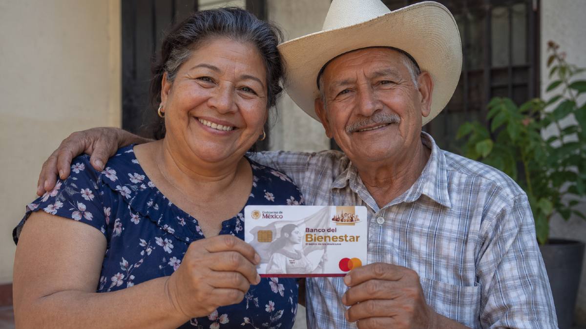 Dos adultos mayores sonriendo mientras sostienen su nueva tarjeta de Bienestar