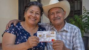 Dos adultos mayores sonriendo mientras sostienen su nueva tarjeta de Bienestar