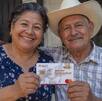 Dos adultos mayores sonriendo mientras sostienen su nueva tarjeta de Bienestar