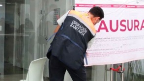 Hombre coloca sello de 'Clausurado' en una clínica de Oaxaca.