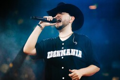 Cantante Eden Muñoz sonriendo mientras sostiene un micrófono durante un concierto con luces de fondo