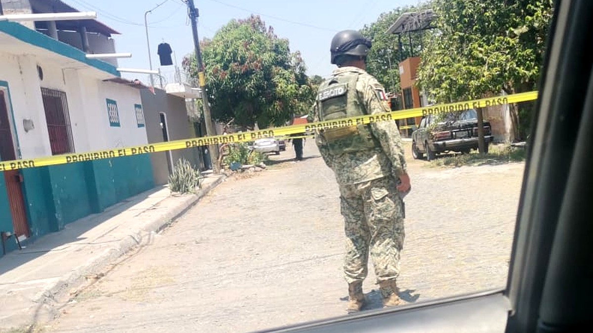 Vista de espaldas de un militar del Ejército Nacional parado detrás de una cinta policiaca en calles de Colima