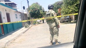 Vista de espaldas de un militar del Ejército Nacional parado detrás de una cinta policiaca en calles de Colima