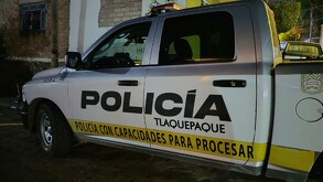 Vista del costado de una patrulla de la Policía Municipal de Tlaquepaque con capacidades para procesar estacionada al lado de una casa