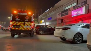 Se observa una ambulancia estacionada y es de noche. Es una plaza comercial.