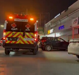 Se observa una ambulancia estacionada y es de noche. Es una plaza comercial.