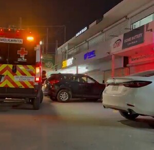 Se observa una ambulancia estacionada y es de noche. Es una plaza comercial.
