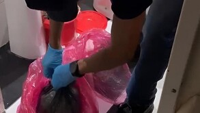 Agente la Policía de Investigación argentina con guantes colocados abriendo bolsas de residuos en una clínica donde se hallaron fetos humanos