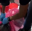 Agente la Policía de Investigación argentina con guantes colocados abriendo bolsas de residuos en una clínica donde se hallaron fetos humanos