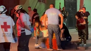 Se observa a varias personas y niños en medio de la calle, hay un señor tendido en el suelo.