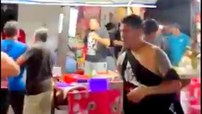 Hombre con la playera rota camina junto a un negocio de comida.