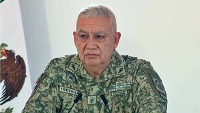 Ricardo Trevilla Trejo, secretario de Defensa Nacional durante conferencia de prensa hablando delante de un podio con micrófono y la bandera de México detrás