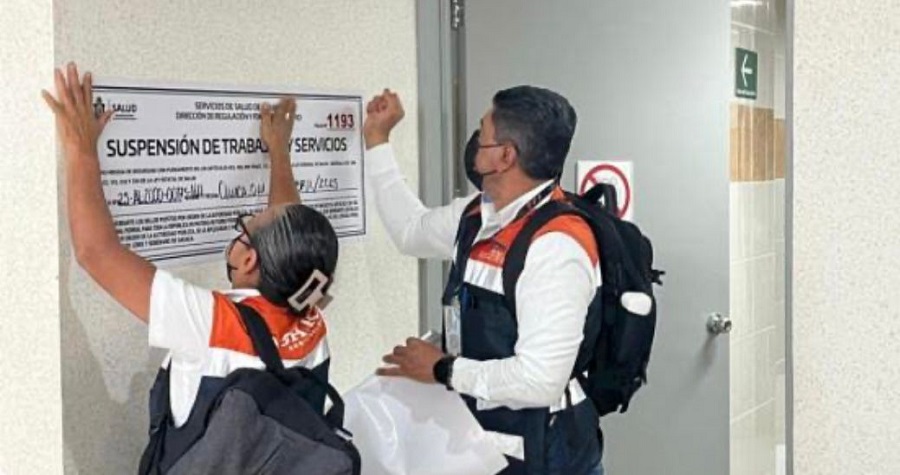Hombre y mujer colocando un sello de suspensión en un edificio de color blanco.