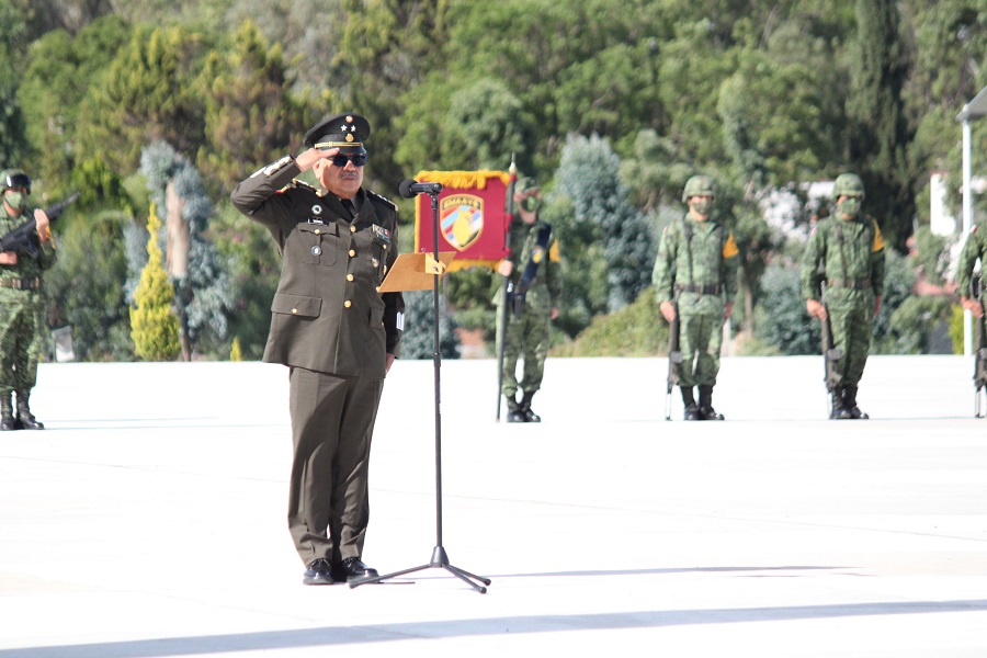 Hombre con traje militar hace un saludo frente a una multitud.