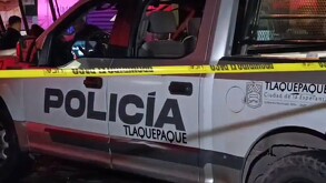 Vista lateral de una patrulla de la Policía Municipal de Tlaquepaque detrás de una cinta policiaca amarilla