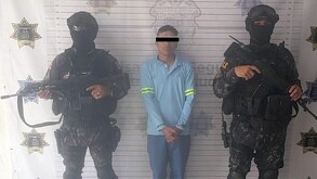 Se observa a dos policías cubiertos de la cara, hay un hombre en medio de ellos.