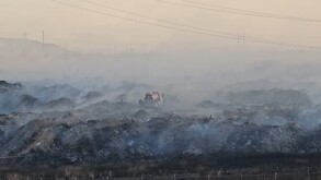 Camión de Protección Civil y Bomberos de Zapopan en medio de un terreno con pilas de pastizal quemándose y emanando humo