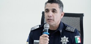 Hombre vestido con uniforme policiaco hablando ante un micrófono.