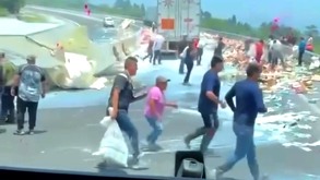 Personas corriendo en la carretera para robar objetos regados en el suelo.