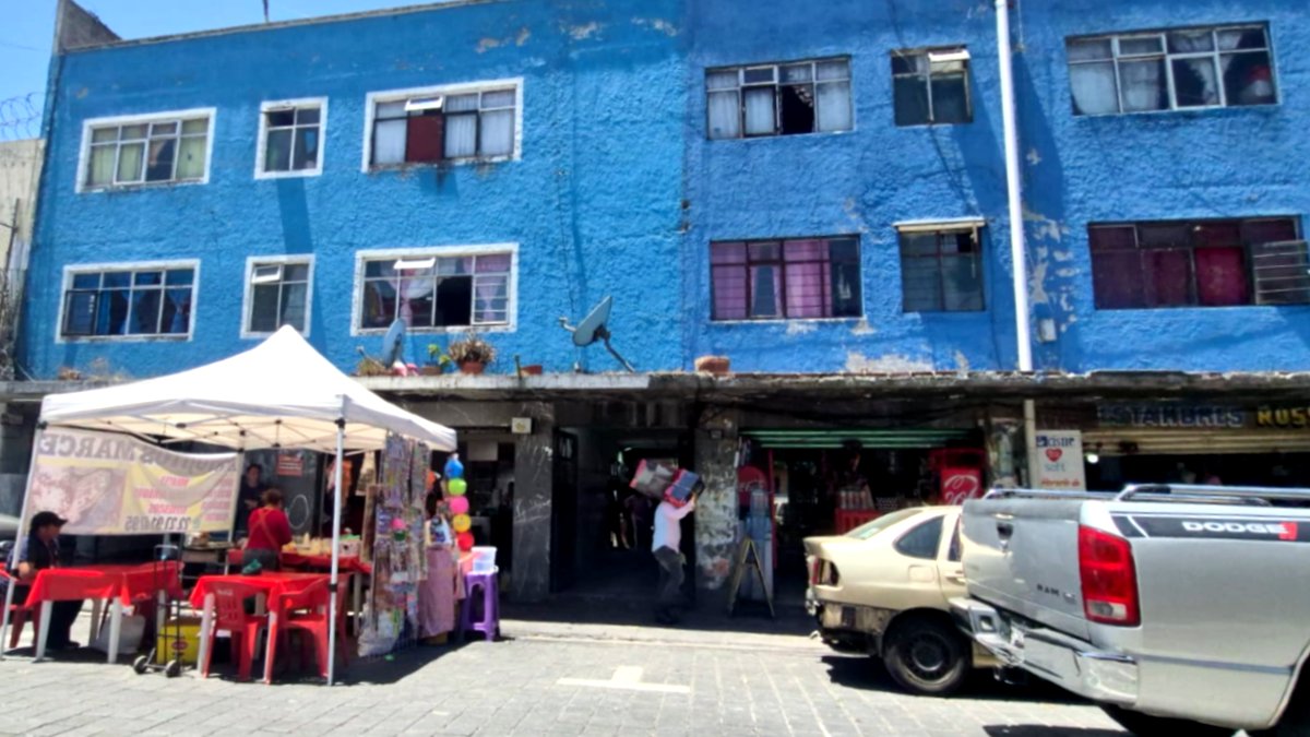 Autos estacionados afuera de un edificio azul en la ciudad de Puebla.