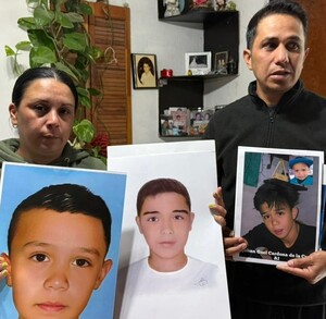 Se observa a un  hombre y una mujer sosteniendo en sus manos fotografías con el rostro de un joven.
