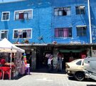 Autos estacionados afuera de un edificio azul en la ciudad de Puebla.