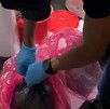 Agente la Policía de Investigación argentina con guantes colocados abriendo bolsas de residuos en una clínica donde se hallaron fetos humanos