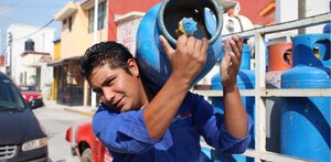 un hombre carga un tanque de gas lp para entregar en una casa en puebla