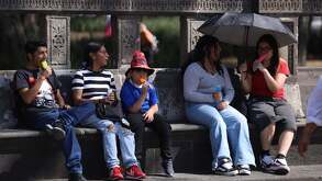 Debido a la ola de calor que se presenta en la capital, una familia se refresca con congeladas en la Alameda Central.