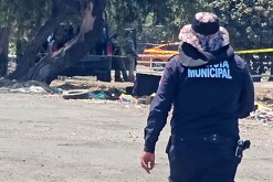 Oficial de la Policía de Tlajomulco visto de espaldas caminando hacia una camioneta con militares del Ejército Mexicano