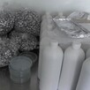 Bolsas con utensilios de química, recipientes de muestra y botellas color blanco sobre una mesa metálica