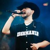 Cantante Eden Muñoz sonriendo mientras sostiene un micrófono durante un concierto con luces de fondo