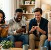 Un grupo de dos hombres y dos mujeres en una sala iluminada mientras miran sus celulares