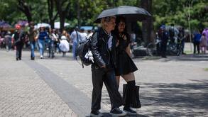 Turistas disfrutan una tarde soleada en Chapultepec con changos de colores y sombrilla para protegerse.