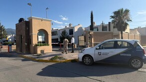 Se observa un carro estacionado, y una fachada de fraccionamiento.