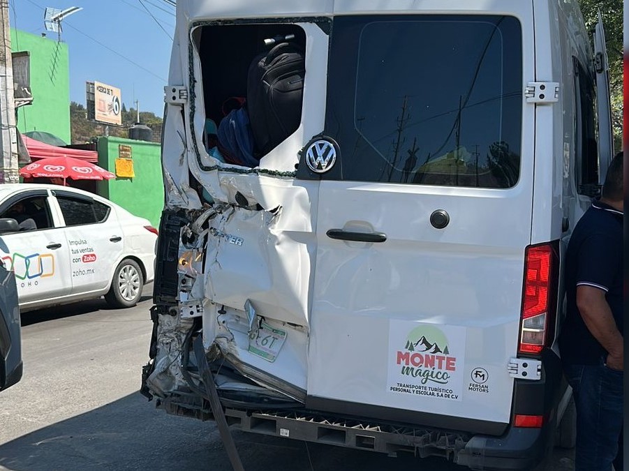 Camioneta blanca de pasajeros vista de la parte de atrás de una con la puerta izquierda aboyada y parcialmente destruida tras ser impactada por tren