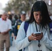 Mujer caminando con el celular en la mano, mientras responde un mensaje.