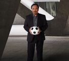 Hugo Sánchez sosteniendo un balón de futbol.