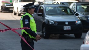 Policía sujeta una cinta roja para impedir el paso a vehículos en una calle de Puebla.
